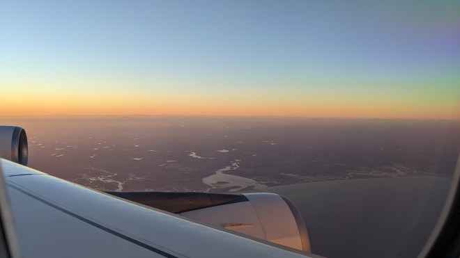 A view out a plane window of sunset over the Maine coast