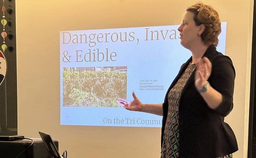 A woman gesturing with her hands standing in front of a presentation projected behind her