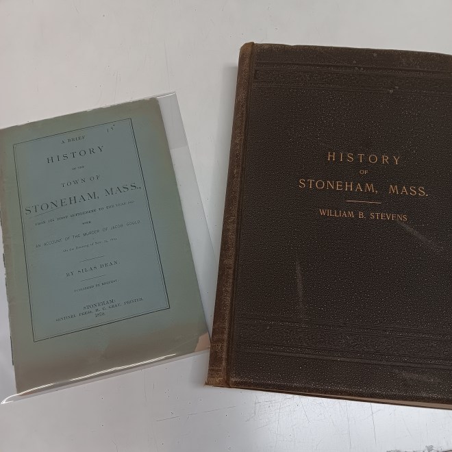 Two old books, a think blue pamphlet on the left and a thicker brown book on the right.