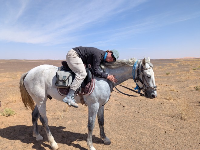 A woman hugging a horses neck from the saddle
