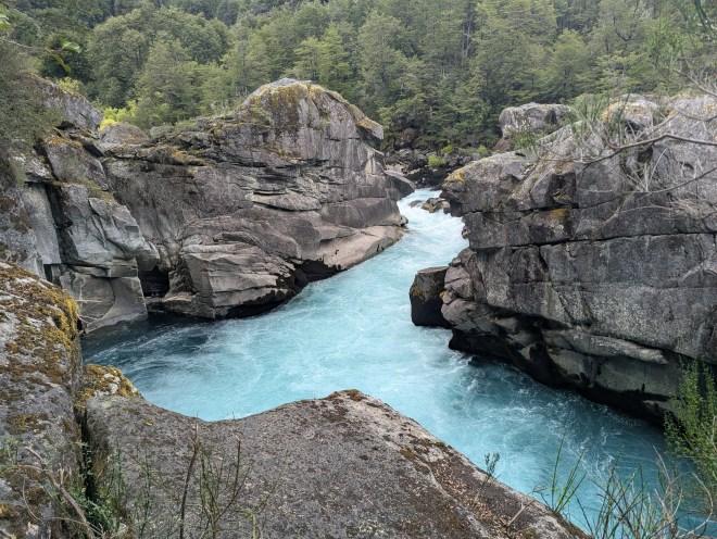 A blue river cutting at almost right angles through steep stone cliffs