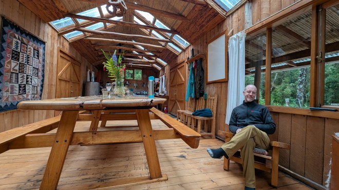 A man sitting on a bench in a big room full of windows and wood