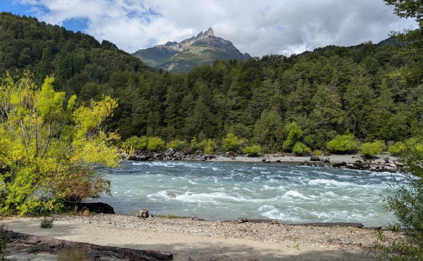 A striking peak behind astonishing blue waters with green hills in the mid ground