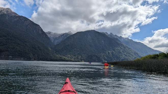 A kayak nose with a kayak in front on a river, with a spectacular mountain cirque above