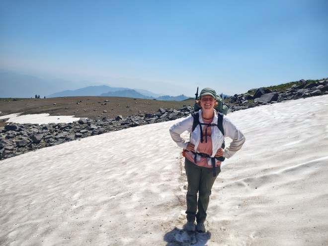 A woman walking across a snow field in the mountains